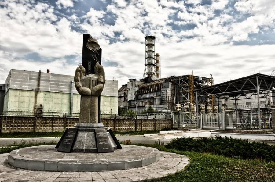 Monument to the Chernobyl catastrophe liquidators with fourth reactor on the background